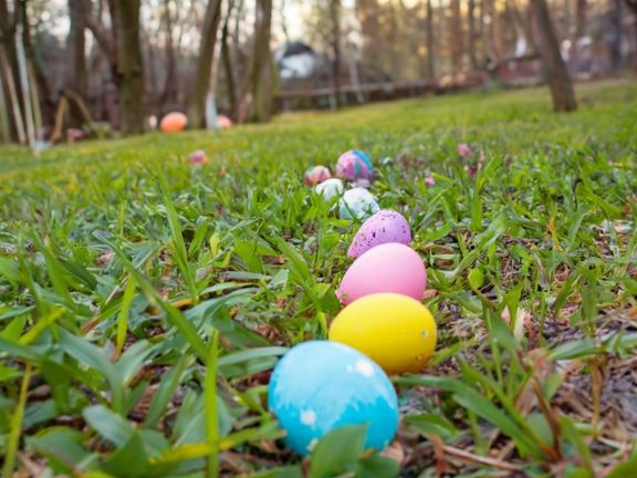 Colorful Easter eggs scattered on green grass in an outdoor setting.