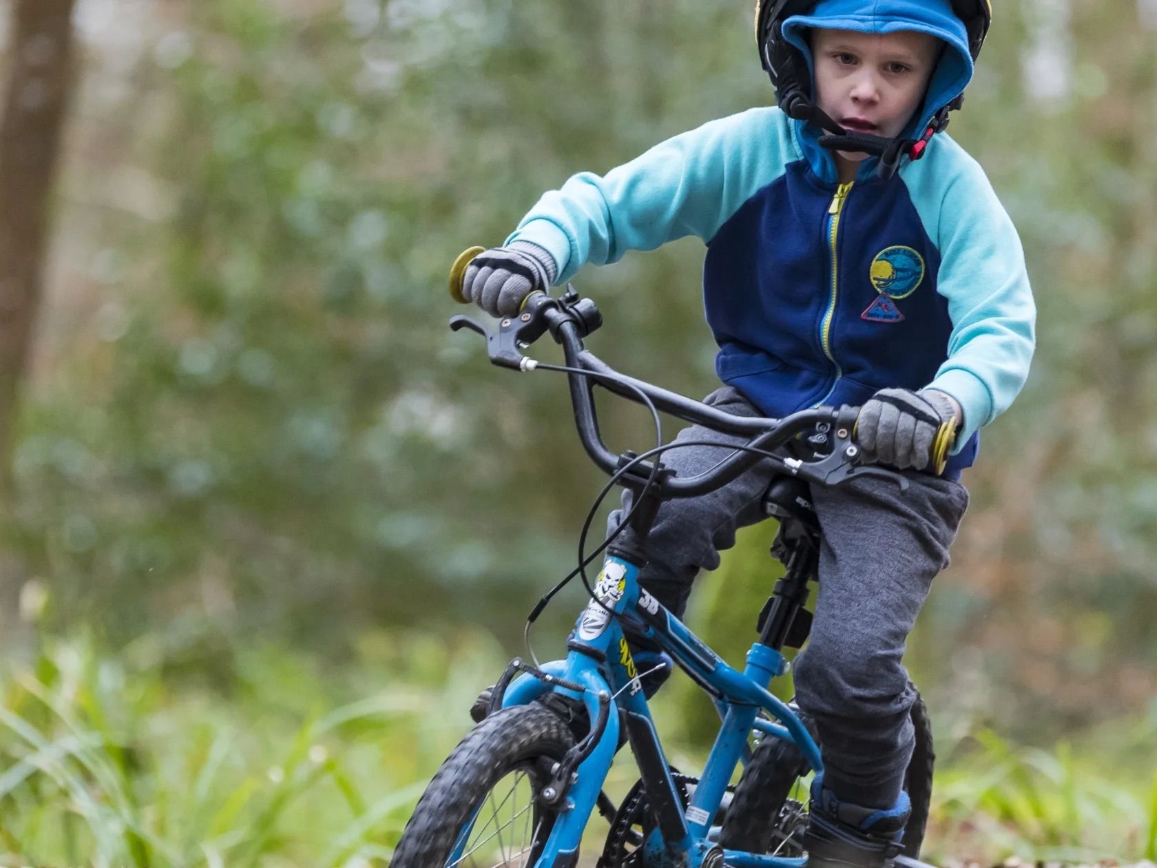 Child riding a bicycle on a forest trail at Lanhydrock, Cornwall.