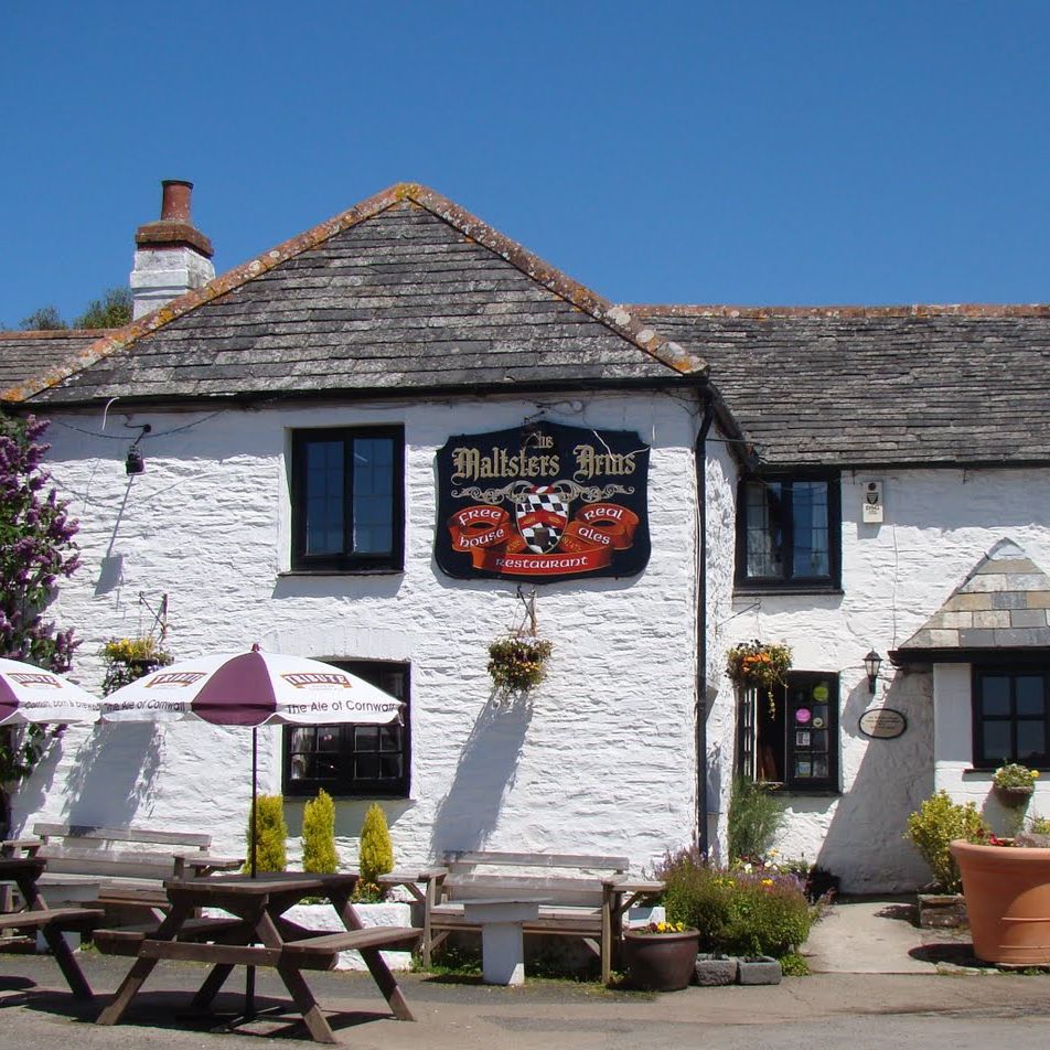 Front view of the Maltsters Arms pub with outdoor seating, white walls, and flower pots