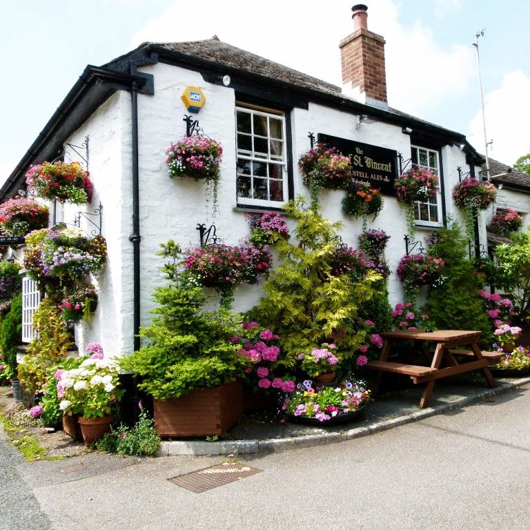 Quaint pub building decorated with vibrant flowers and hanging baskets on the exterior.