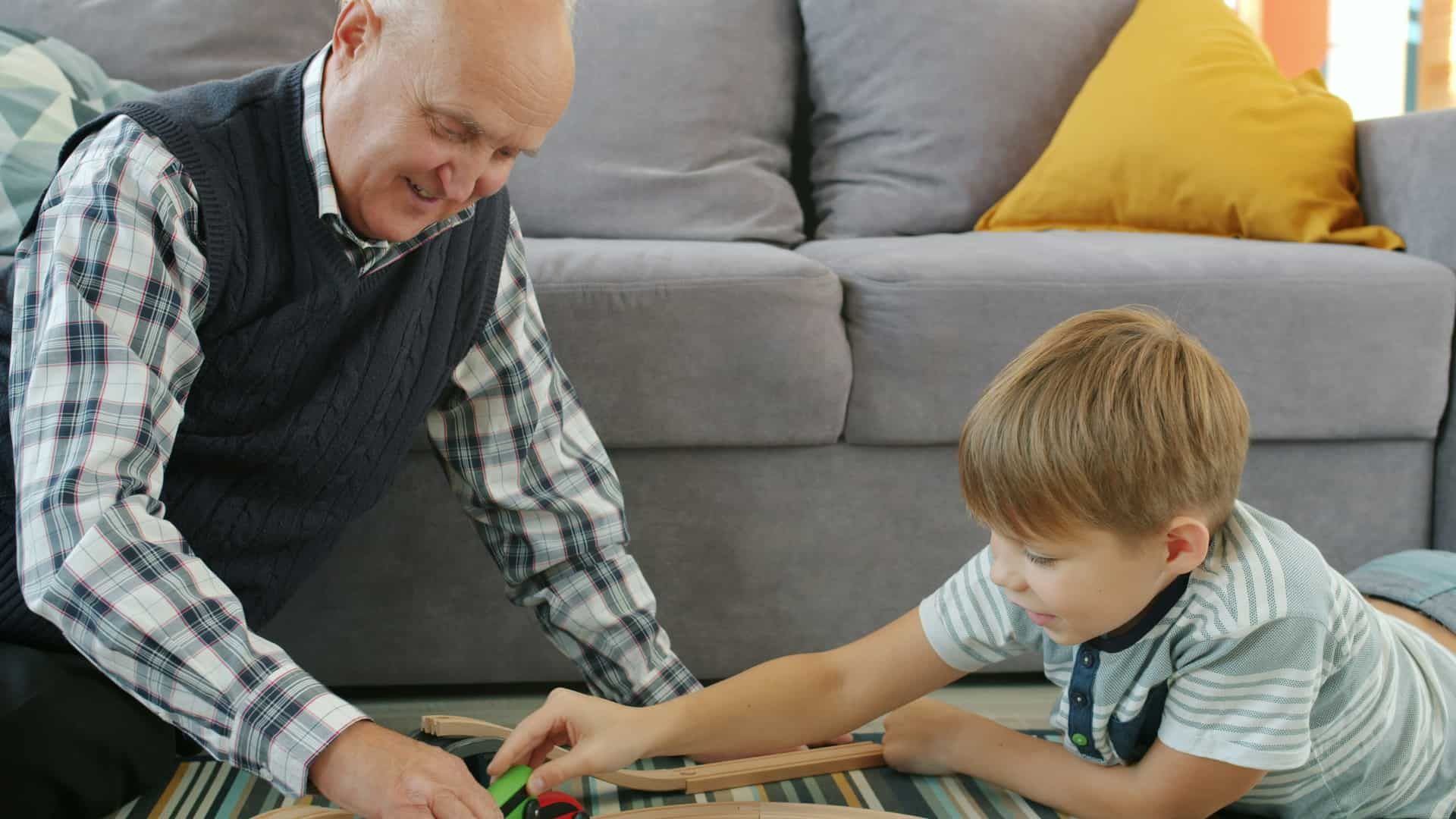 Grandfather and grandson playing with a toy train on the floor