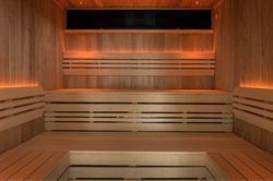 Interior of a modern wooden sauna with tiered benches and soft ambient lighting.