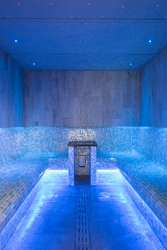 Modern blue-tiled steam room with built-in seating, under-bench lighting, and a starry effect ceiling.