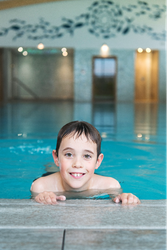 Smiling boy holding on to the edge of an indoor swimming pool