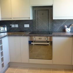 Modern kitchen with grey countertops, built-in oven, electric stove, toaster, and decorative utensils on the counter.