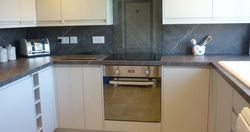Modern kitchen with grey countertops, built-in oven, electric stove, toaster, and decorative utensils on the counter.