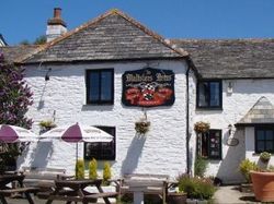 White stone building with the sign 'Maltsters Arms', outdoor seating, and umbrellas.