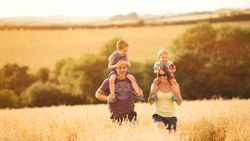 Family with two young children enjoying a walk in a sunny field