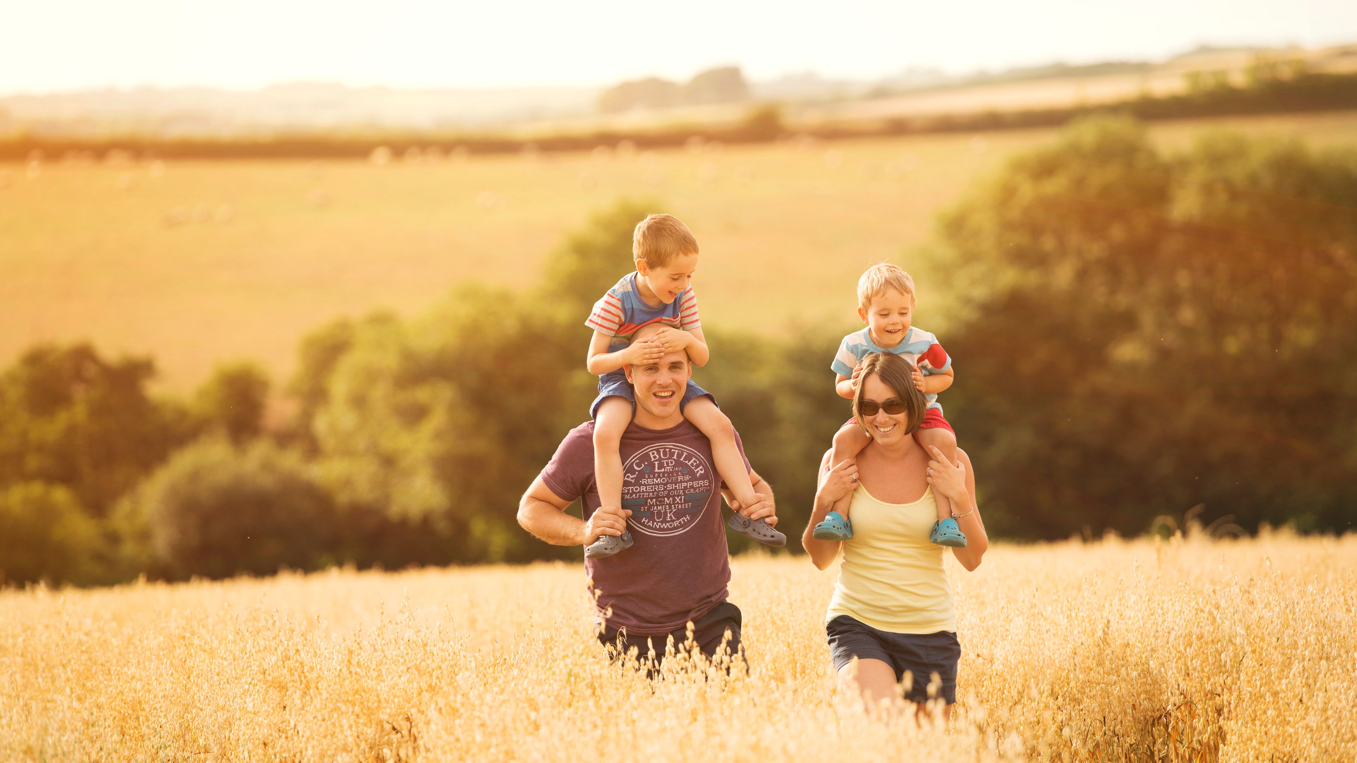Family with two young children enjoying a walk in a sunny field