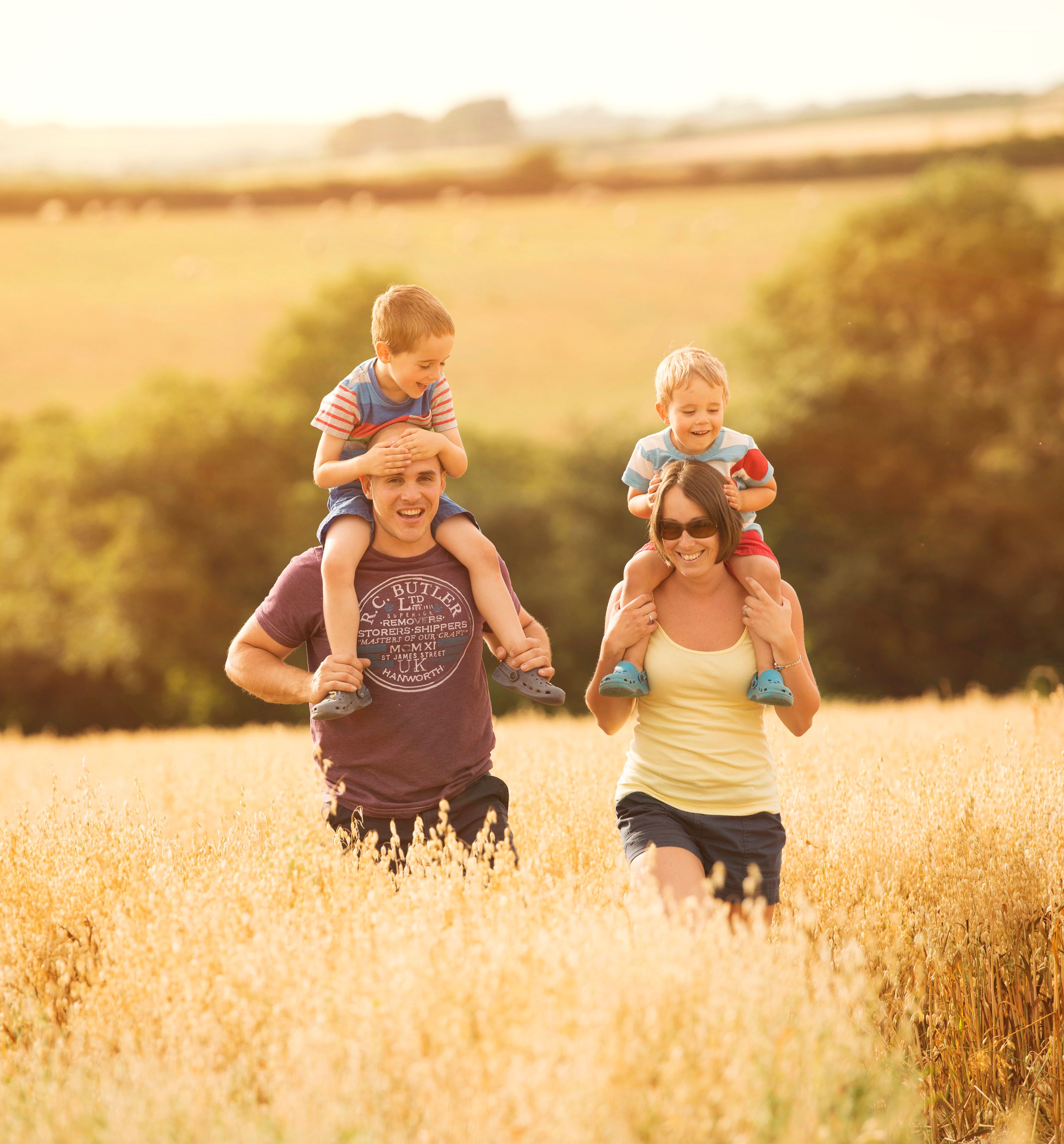 Family with two young children enjoying a walk in a sunny field