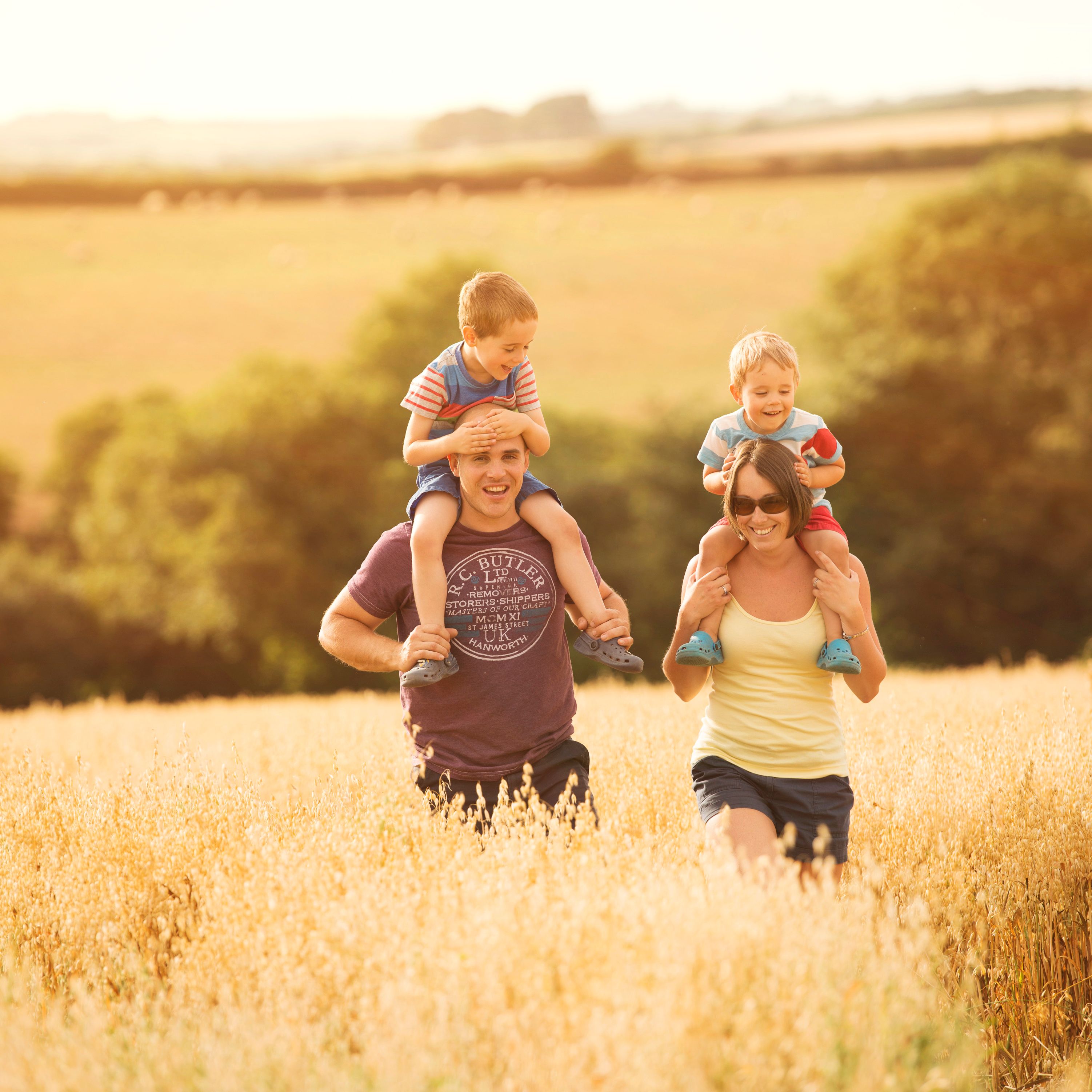 Family with two young children enjoying a walk in a sunny field