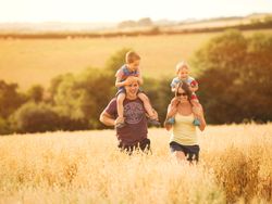 Family with two young children enjoying a walk in a sunny field