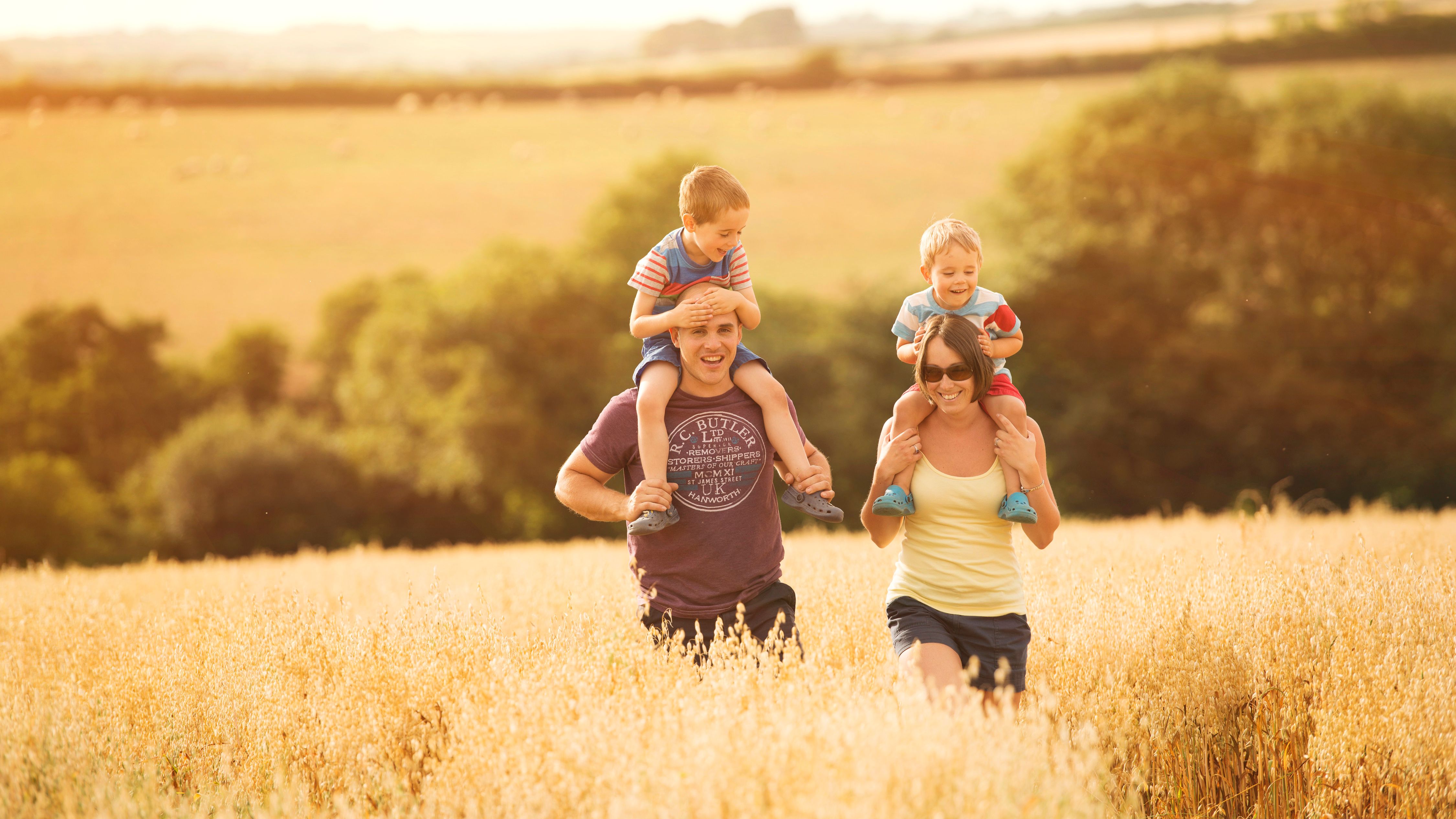 Family with two young children enjoying a walk in a sunny field