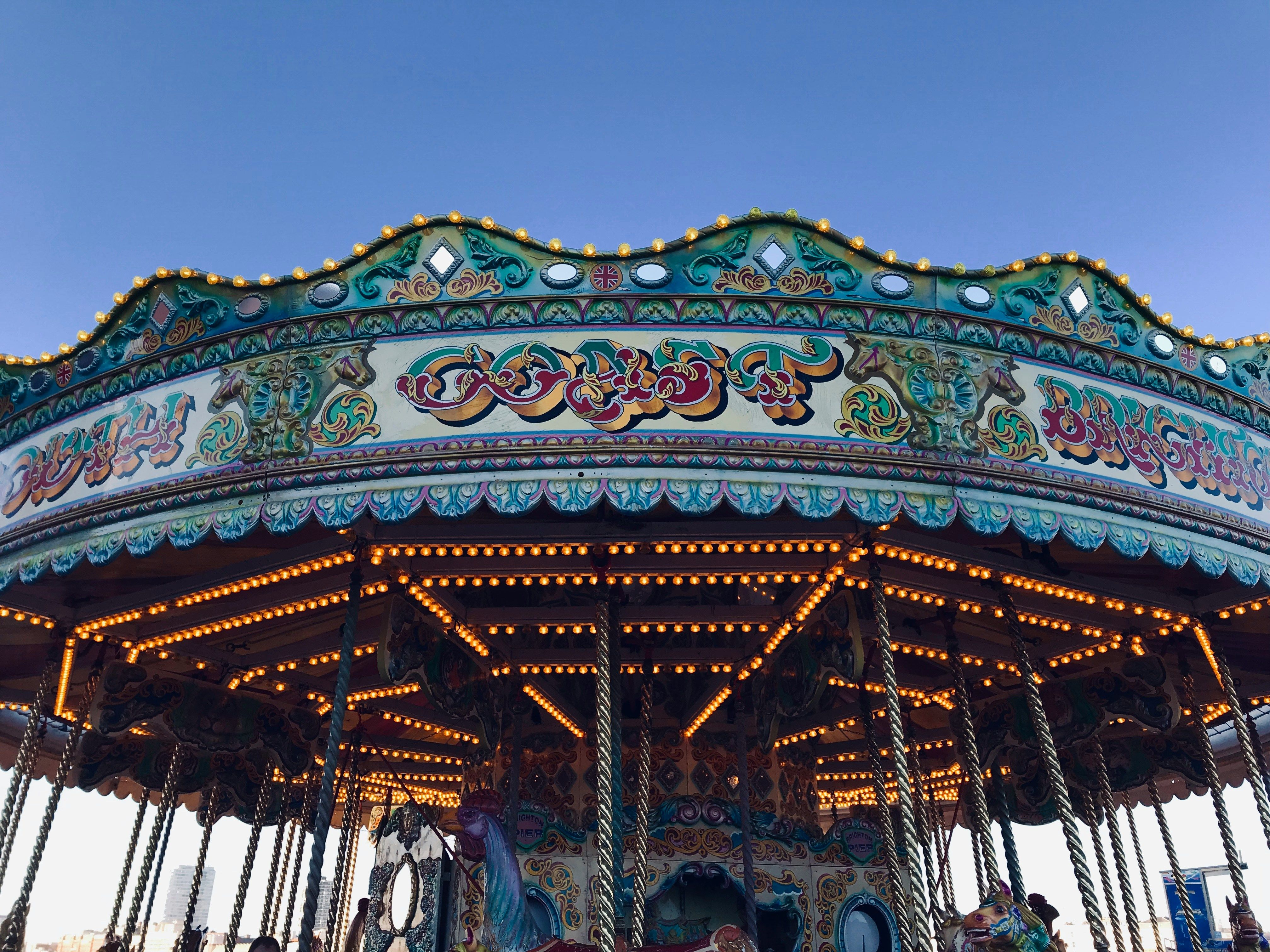 Vintage carousel with ornate decorations and lights against a clear blue sky