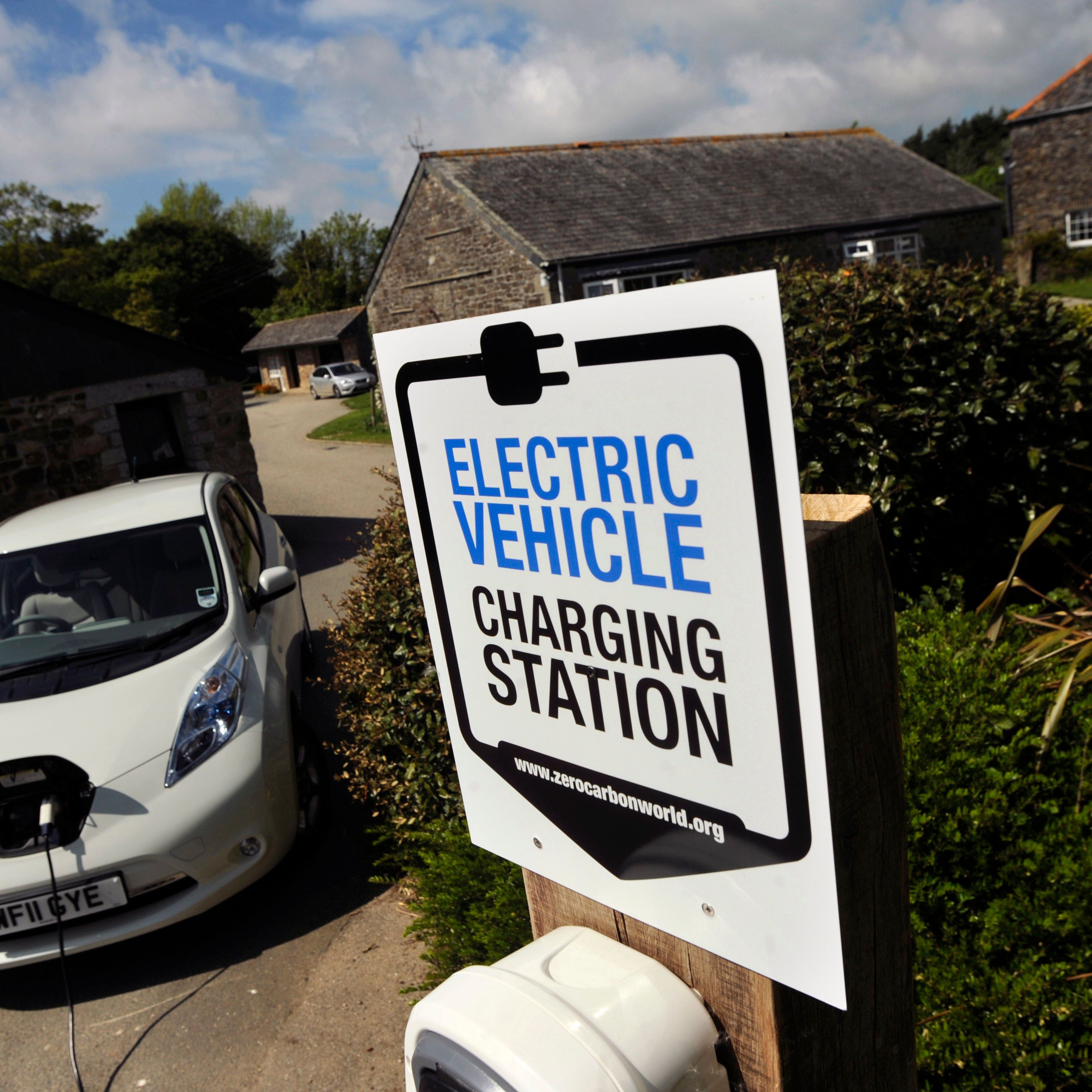 Electric vehicle charging station sign with a white electric car charging nearby