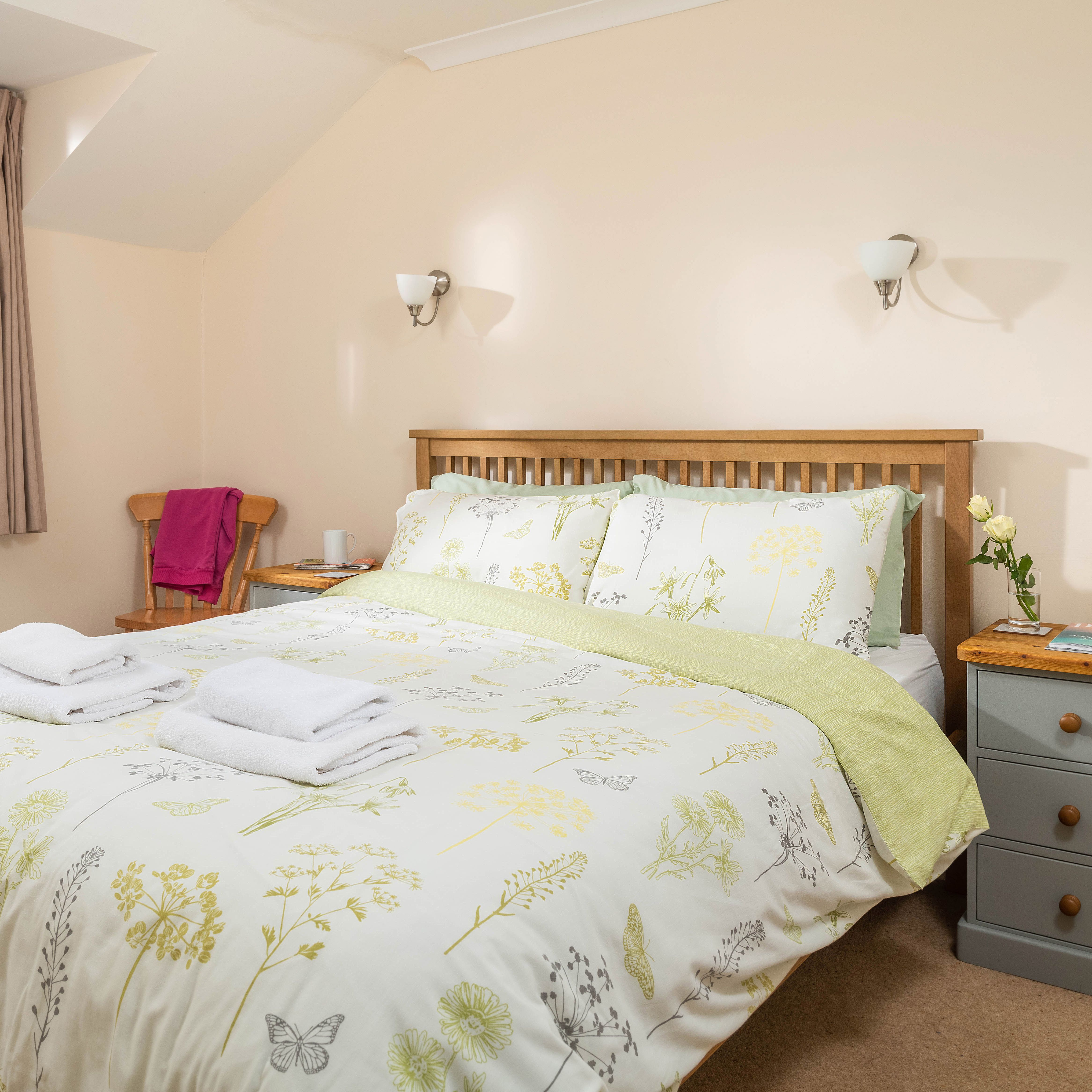 Cozy bedroom with floral bedding, wooden bed frame, bedside table, and window