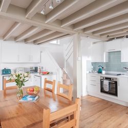Modern kitchen and dining area with wooden table, white cabinets, and exposed ceiling beams