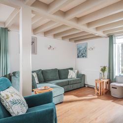 Cozy living room with green sofas, wooden floor, TV, and large window with green curtains