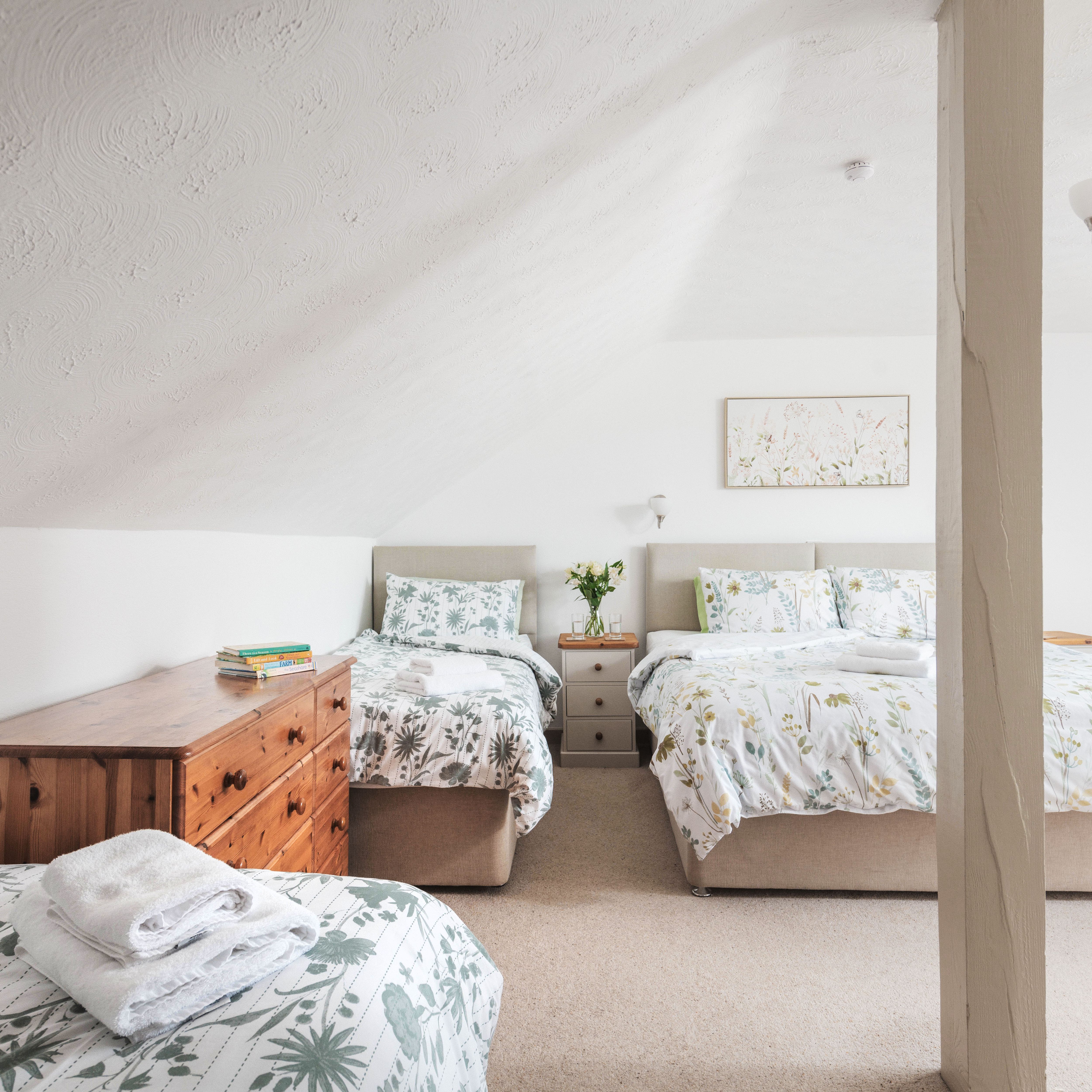 Cozy attic bedroom with three beds and floral bedding