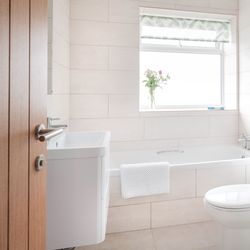 Bright, modern bathroom with a bathtub, sink, toilet, and glass shower enclosure.