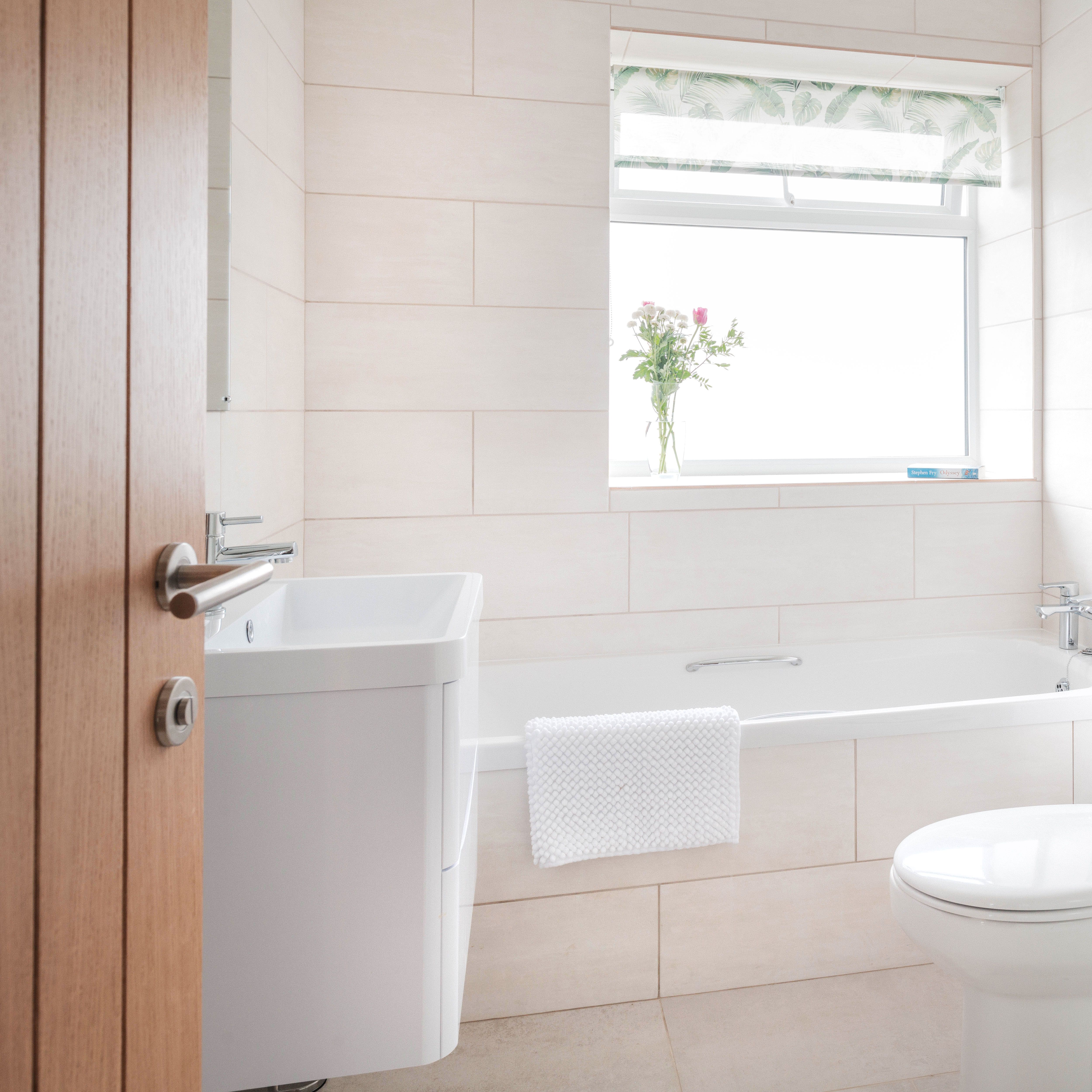 Bright, modern bathroom with a bathtub, sink, toilet, and glass shower enclosure.