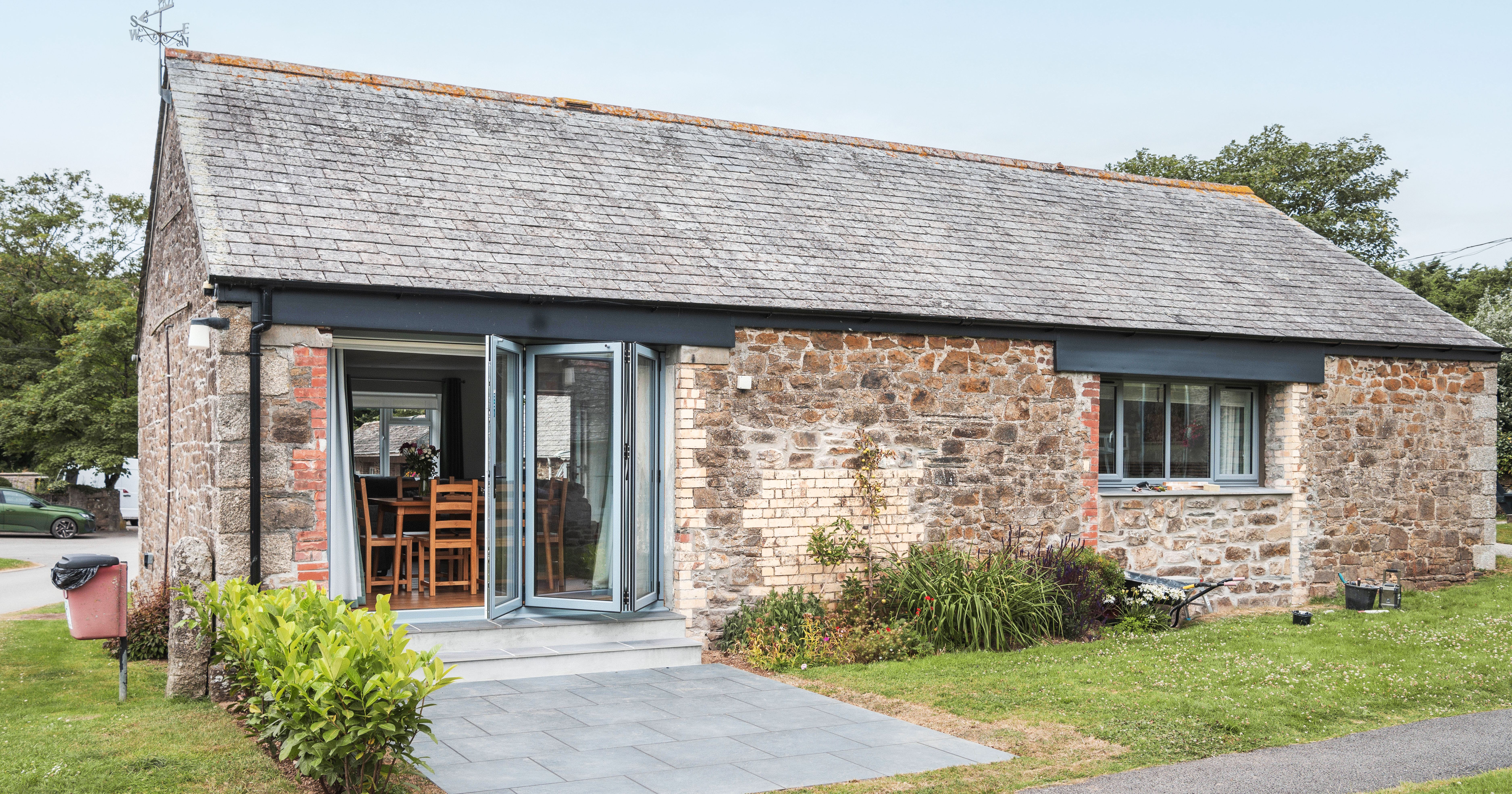 Renovated stone stable with large patio doors and a small garden