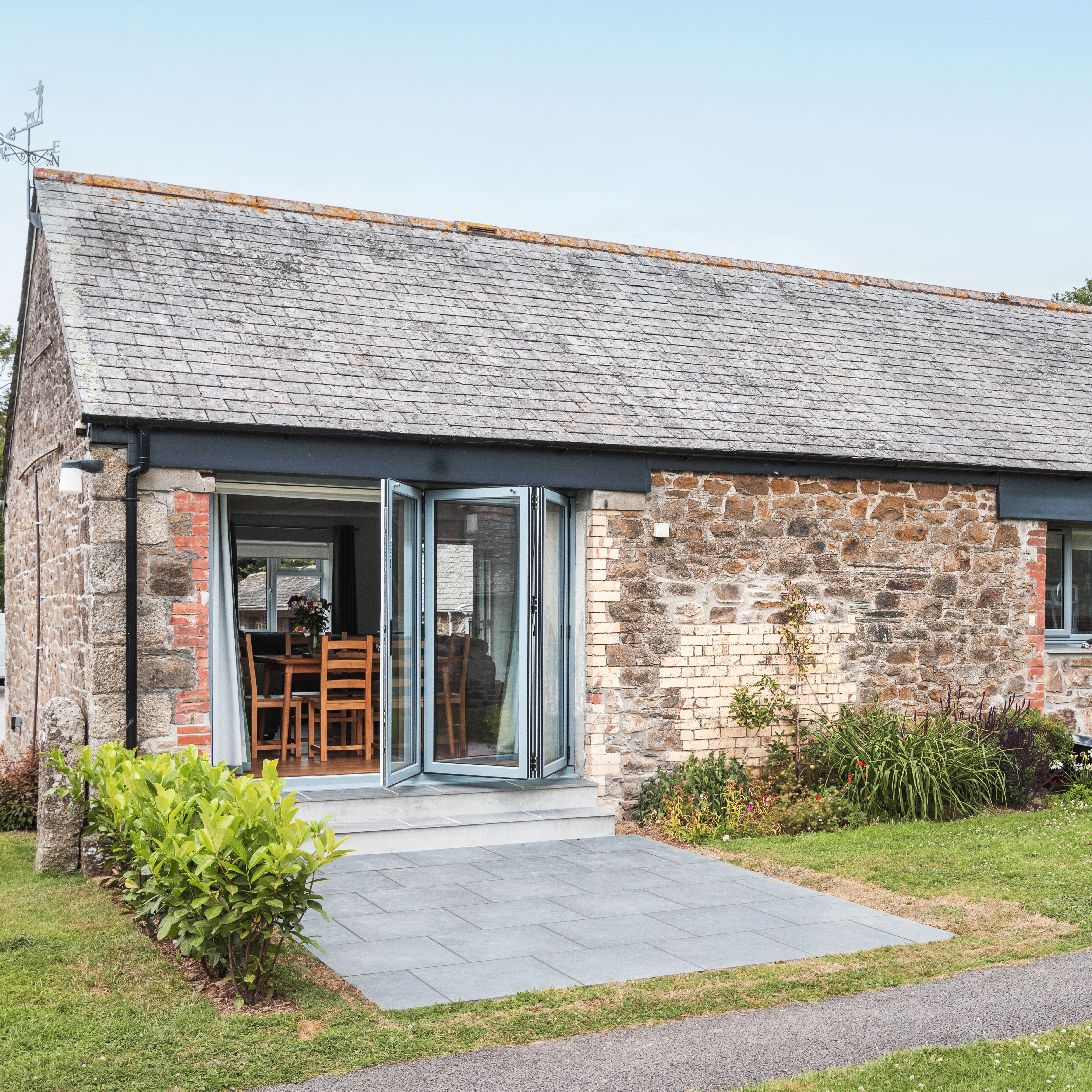 Renovated stone stable with large patio doors and a small garden