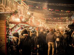 A crowded Christmas market at night with festive lights and decorated stalls.