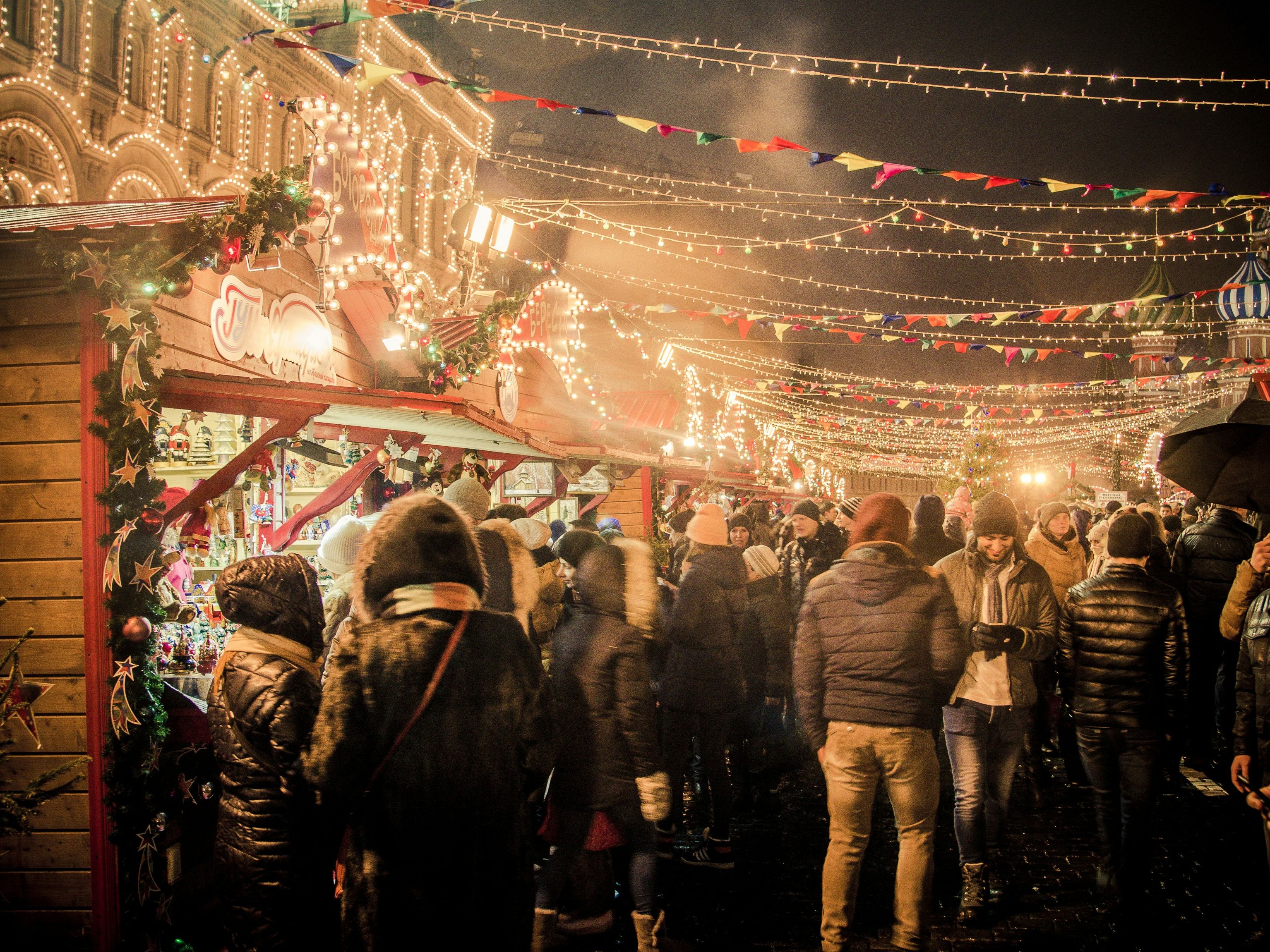 A crowded Christmas market at night with festive lights and decorated stalls.