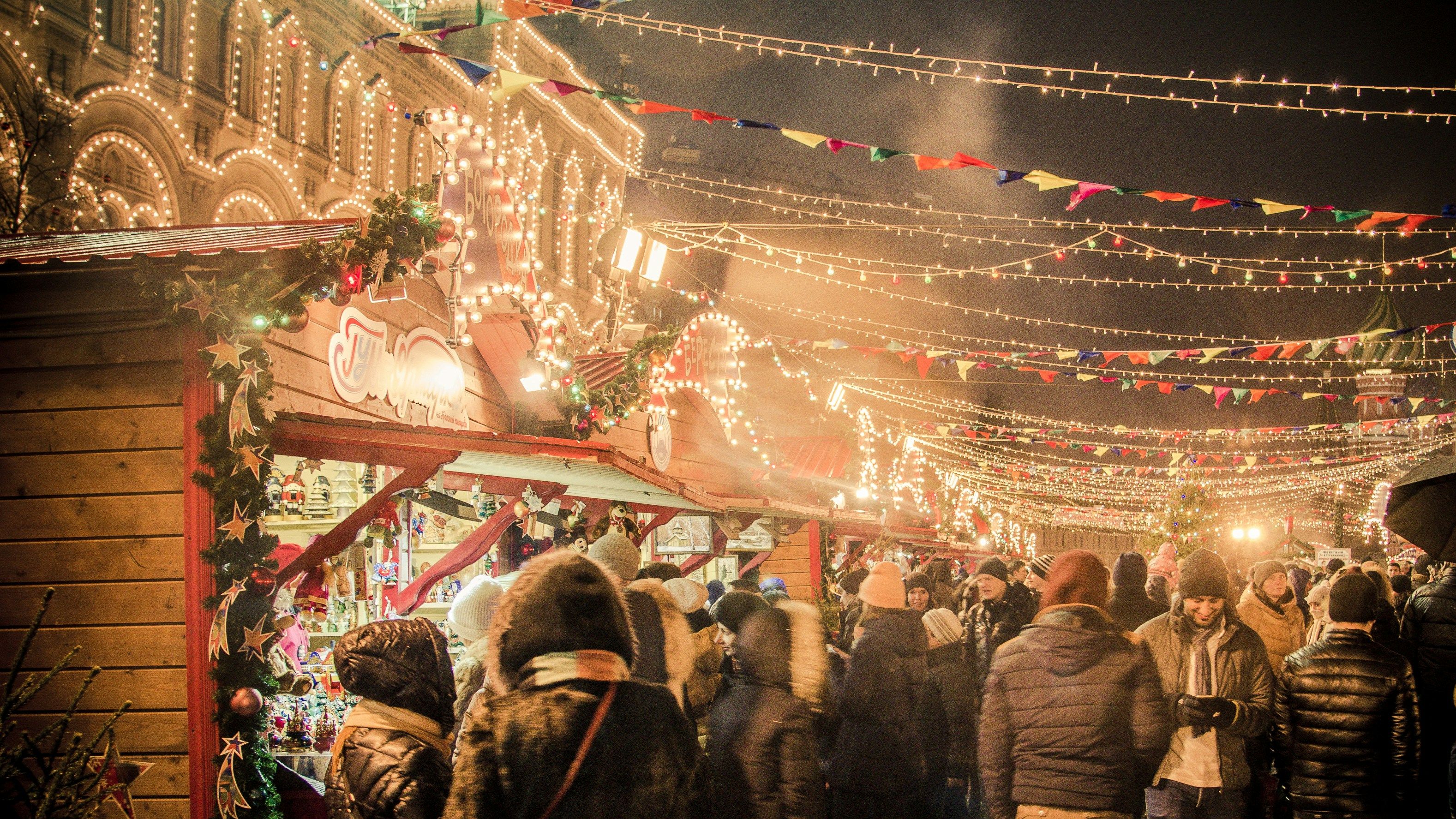 A crowded Christmas market at night with festive lights and decorated stalls.