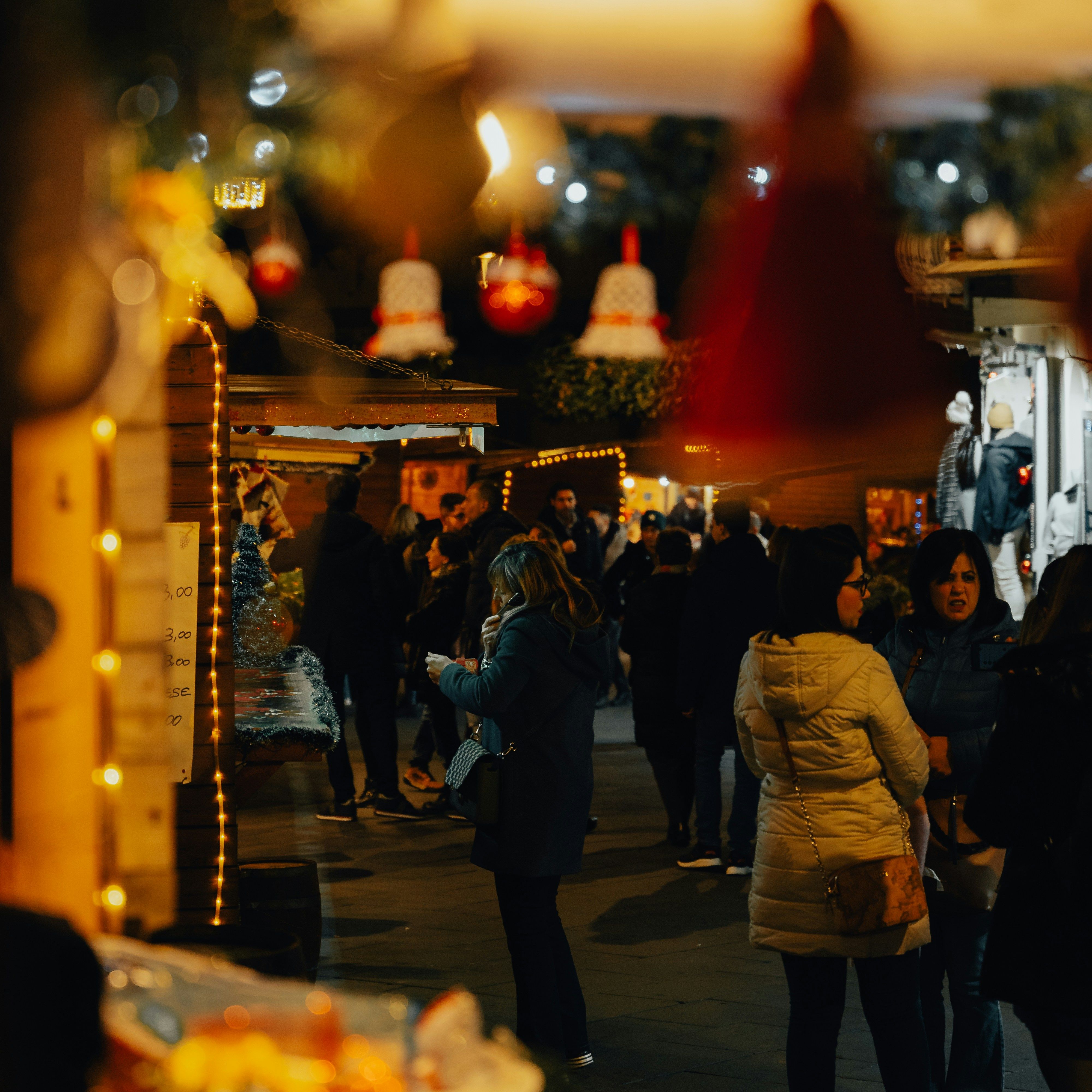 People enjoying a festive outdoor market at night with holiday lights and decorations
