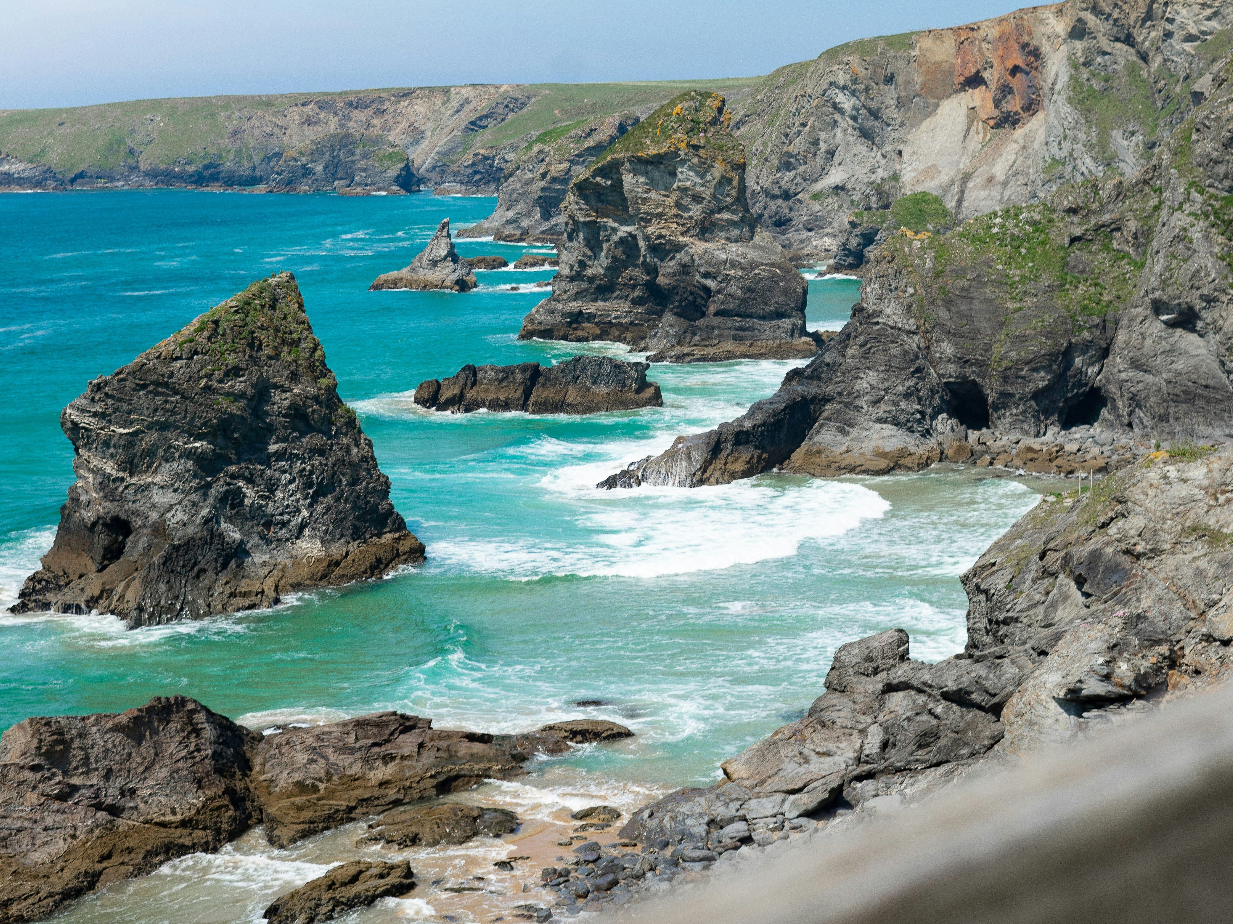 Rocky coastline with dramatic cliffs and turquoise sea under a clear blue sky.