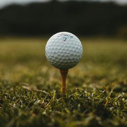 Close-up of a golf ball on a wooden tee on a grassy field