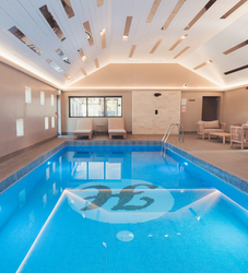Indoor swimming pool with lounge chairs and modern ceiling design