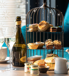 Afternoon tea setup with champagne, pastries, sandwiches, and desserts on a tiered stand.