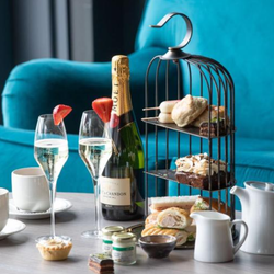 Afternoon tea setup with champagne, pastries, sandwiches, and tea service on a table