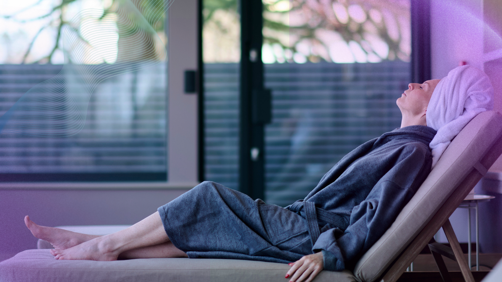 Woman relaxing in a spa lounge chair wearing a bathrobe and towel on her head