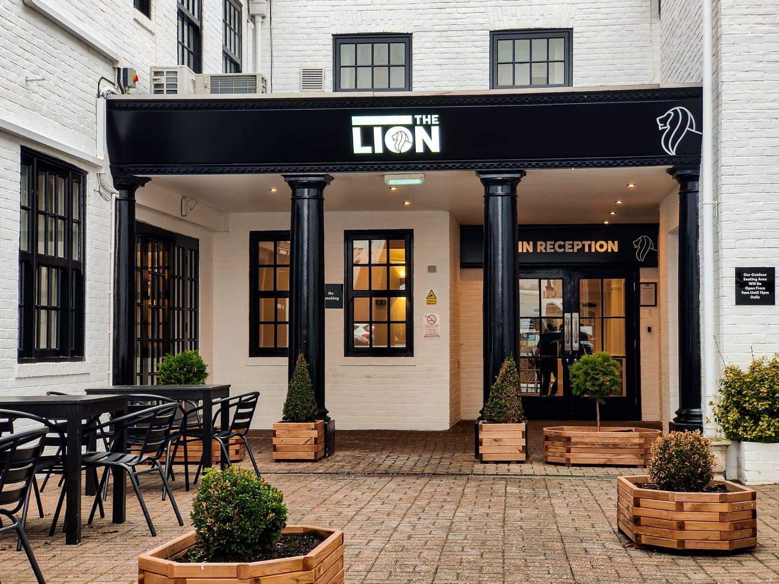 Entrance to The Lion hotel with outdoor seating and black columns