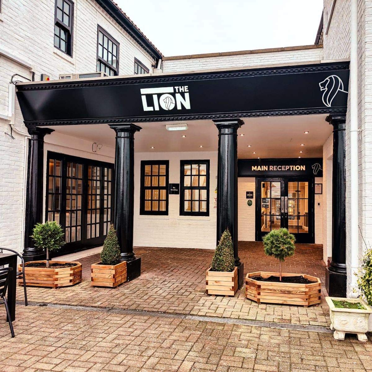 Main entrance of The Lion hotel with black pillars and sign, leading to the main reception