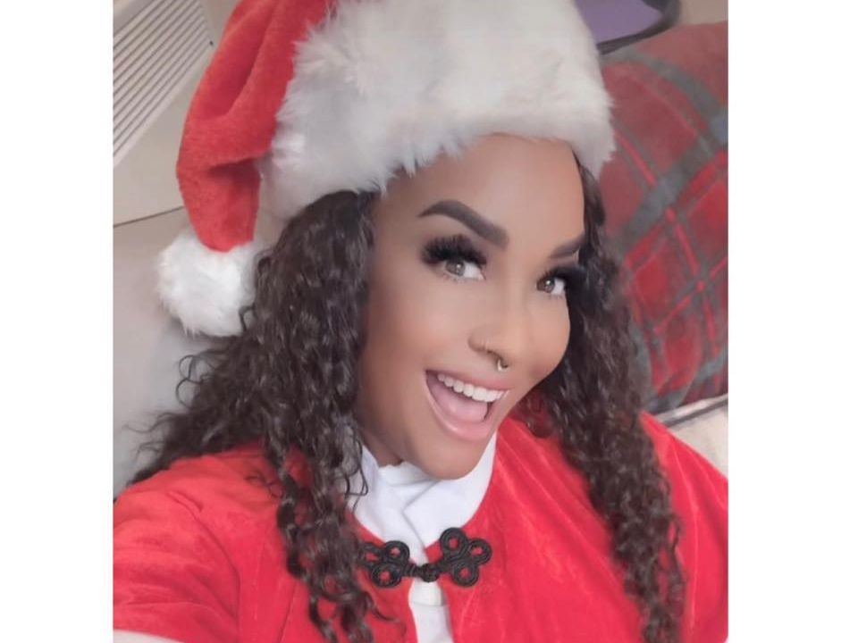 Person wearing a Santa hat and Santa outfit, smiling at the camera.