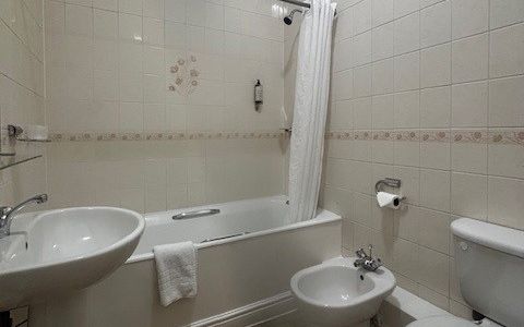 A small bathroom with a bathtub, sink, toilet, and bidet.