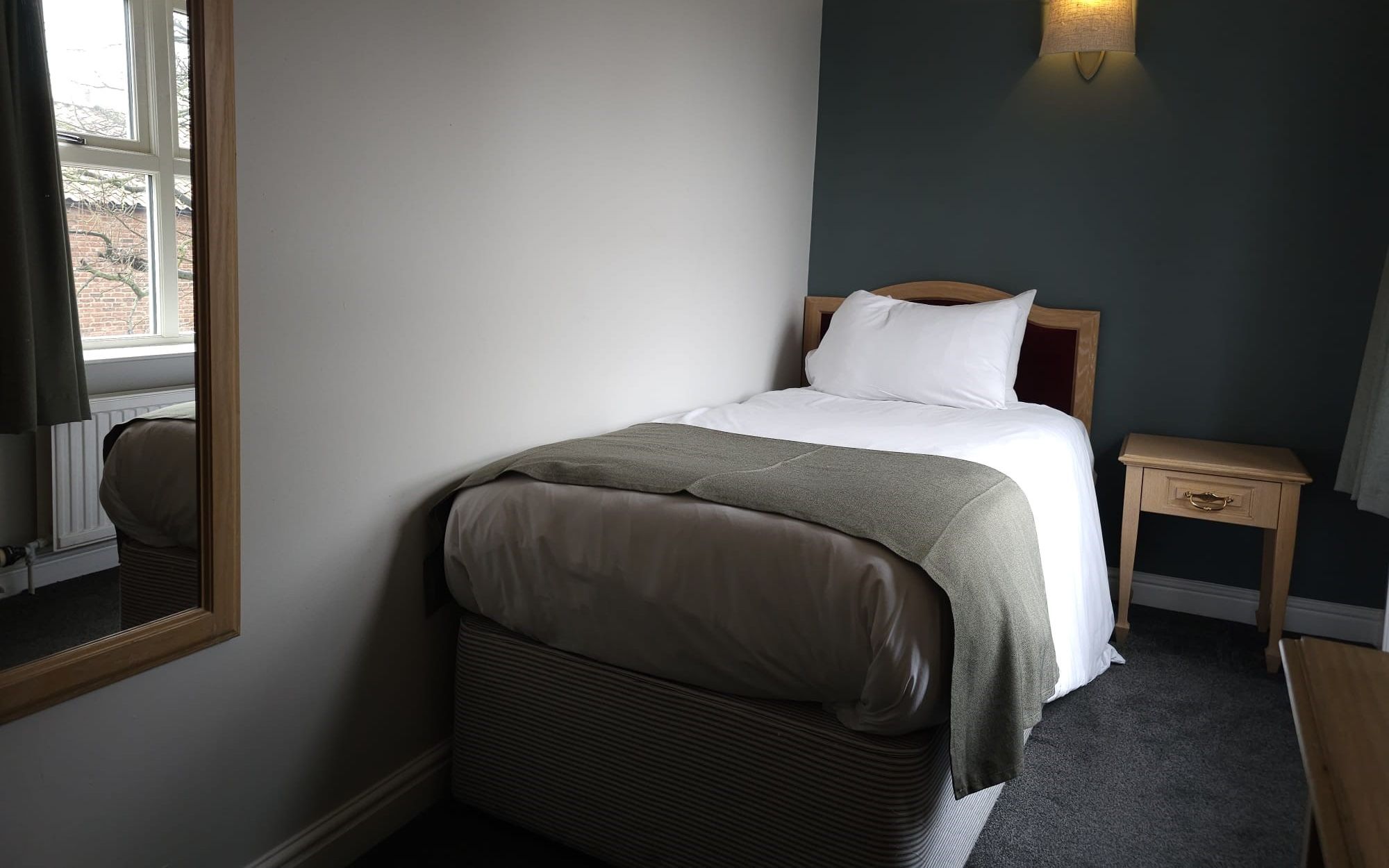 Cozy single bedroom with a bed, bedside table, and wall lamp