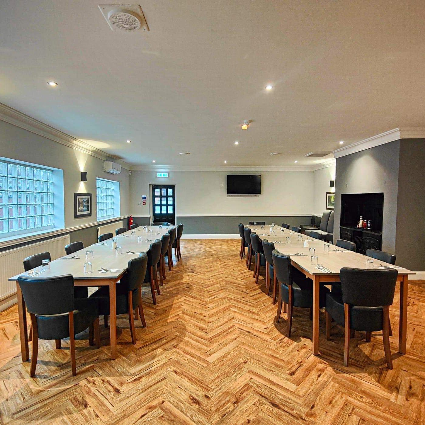 Modern conference room with two long tables and several chairs arranged in a U-shape.