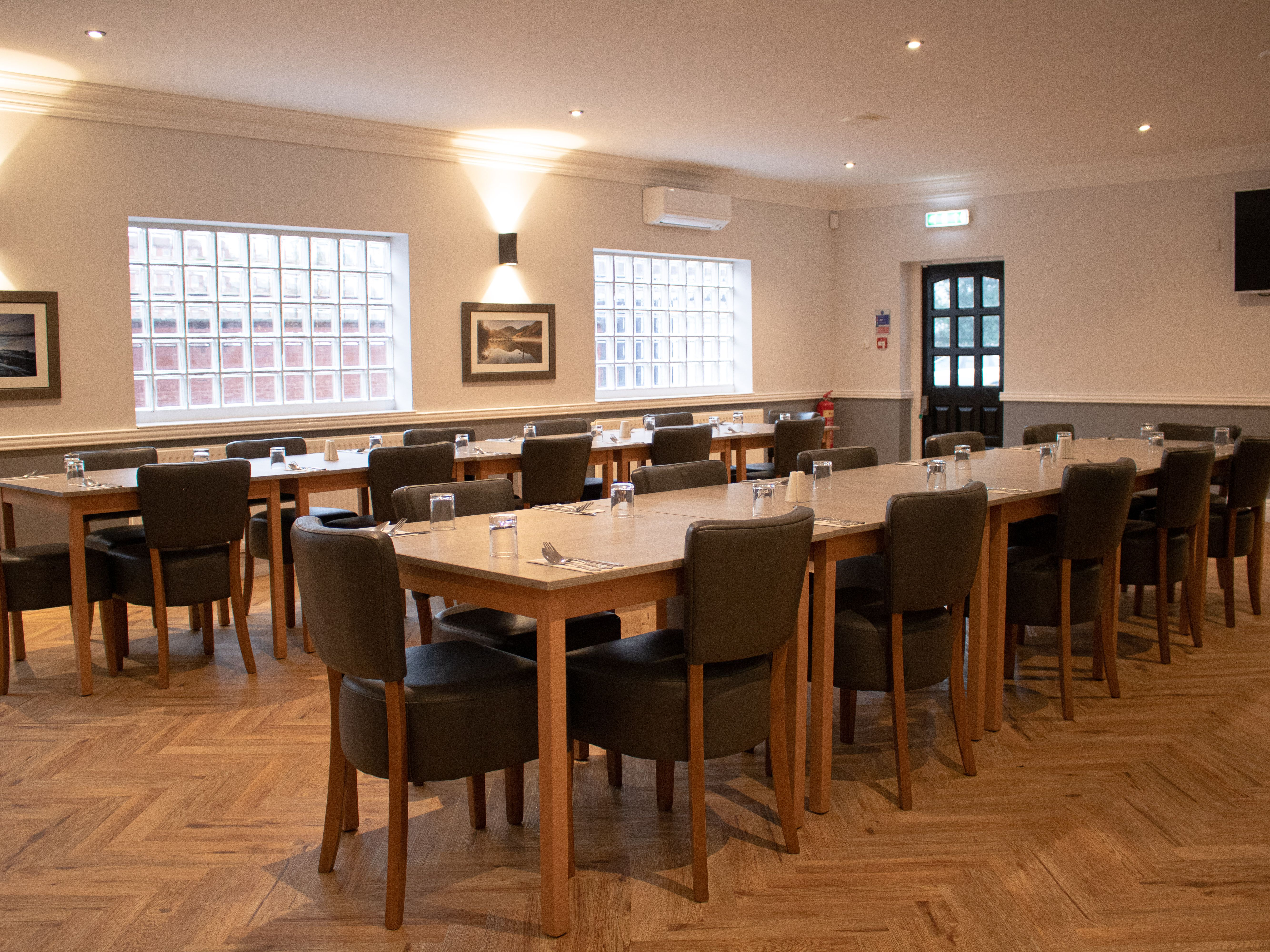 Spacious event room with modern decor, set up with tables and chairs for a meeting or dining event.