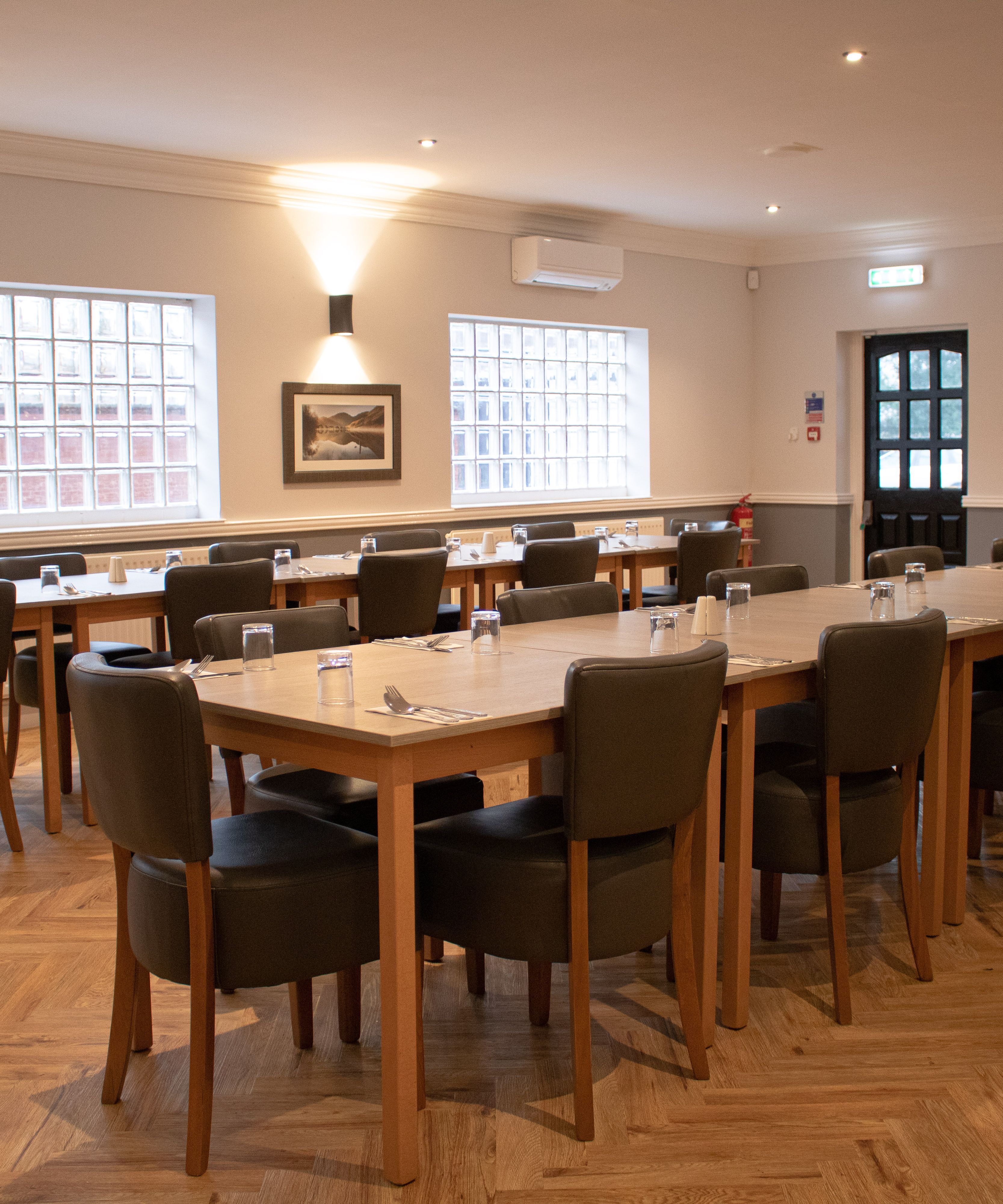 Spacious event room with modern decor, set up with tables and chairs for a meeting or dining event.
