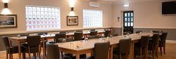 Spacious event room with modern decor, set up with tables and chairs for a meeting or dining event.