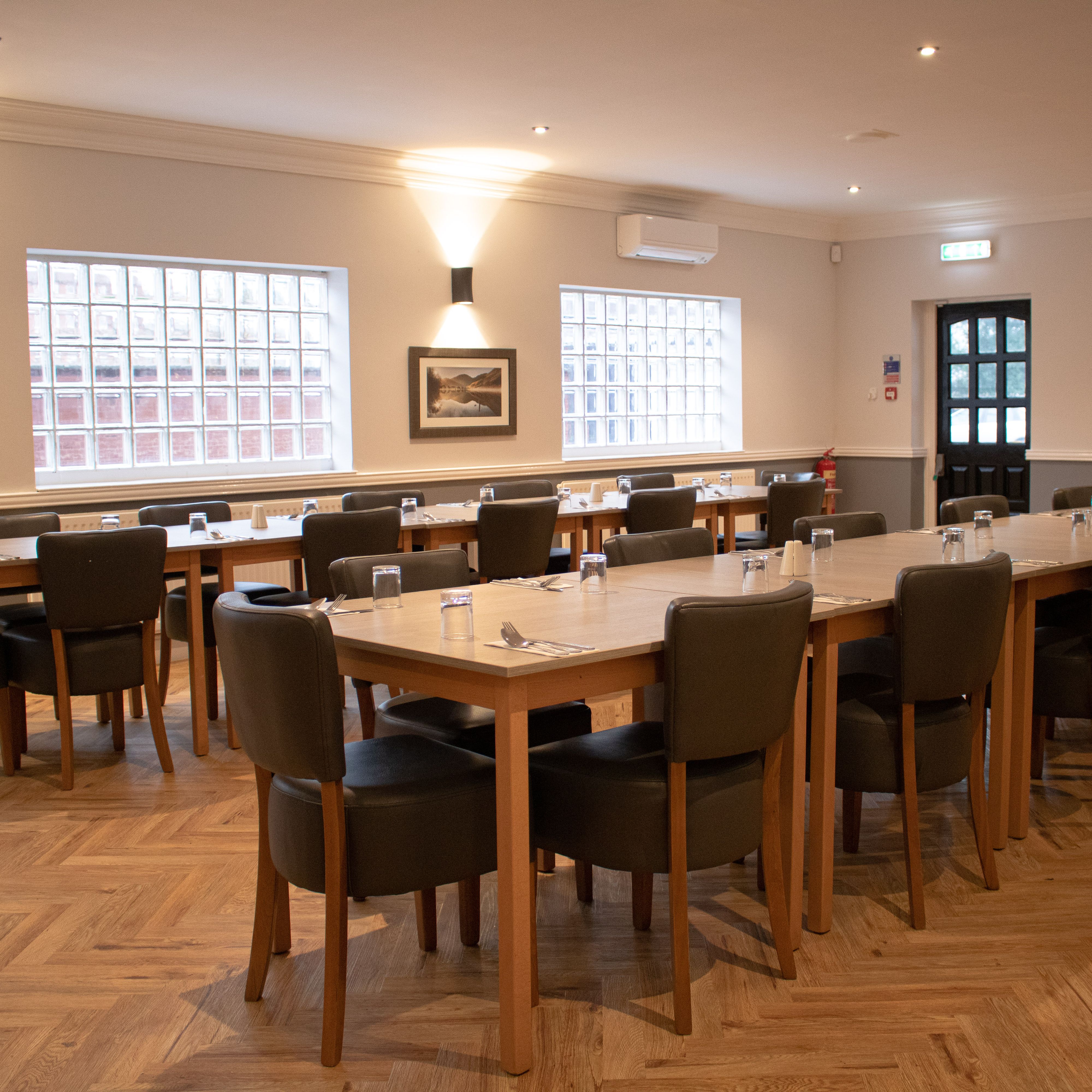 Spacious event room with modern decor, set up with tables and chairs for a meeting or dining event.