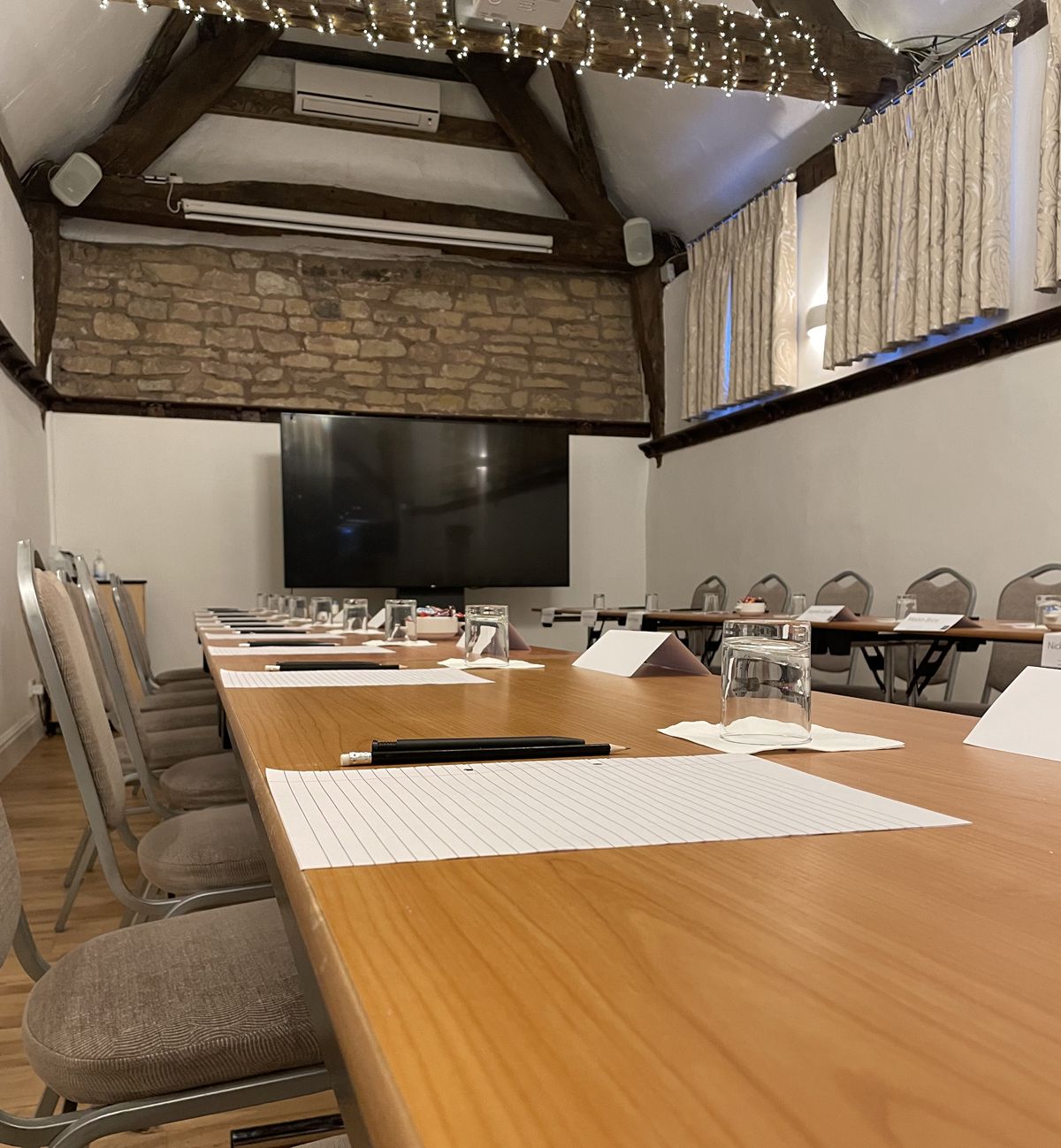 Empty conference room with long table, chairs, notepads, and glasses of water