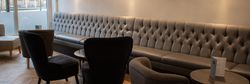Interior of a modern restaurant or lounge with tufted bench seating and velvet chairs