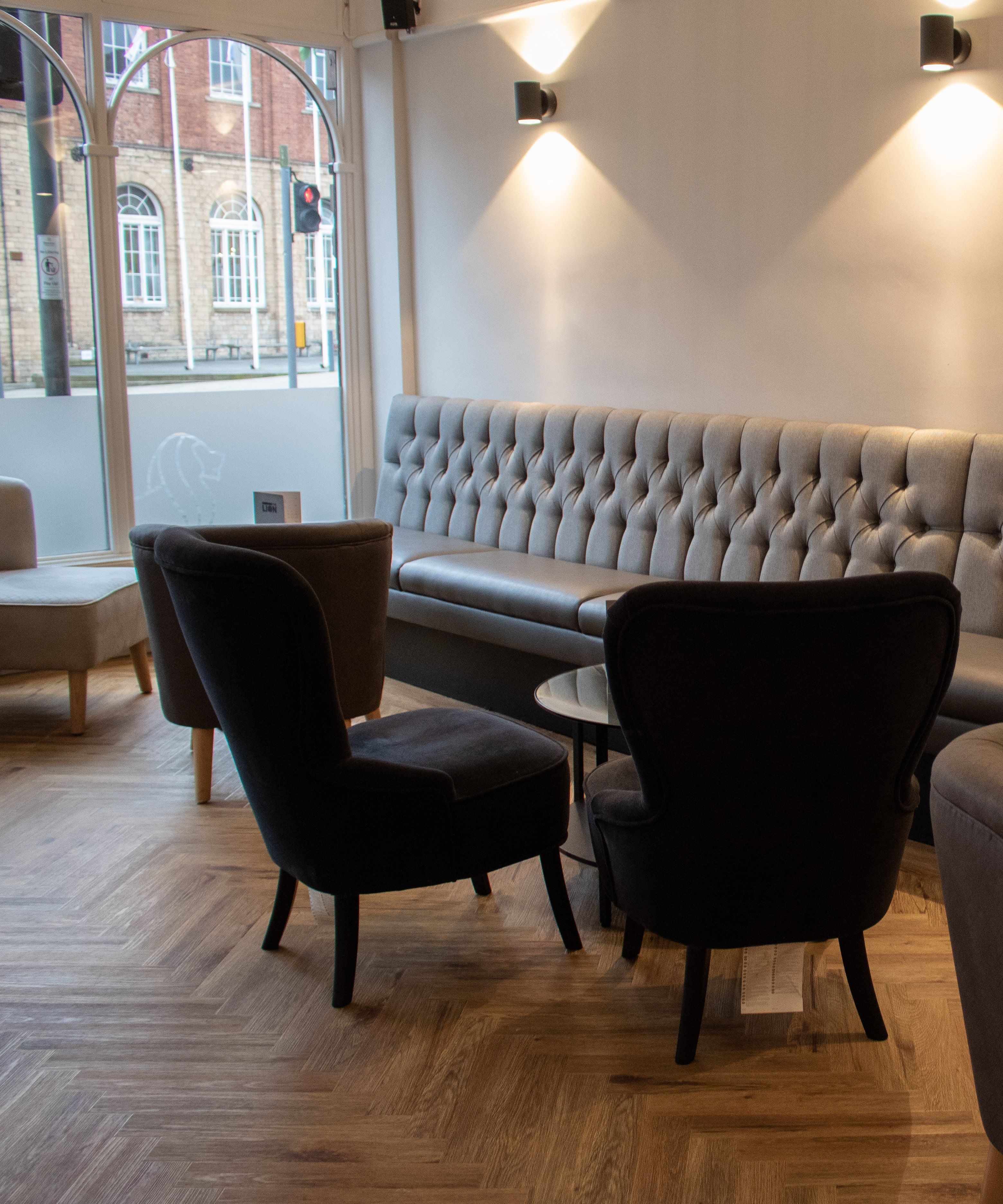 Interior of a modern restaurant or lounge with tufted bench seating and velvet chairs